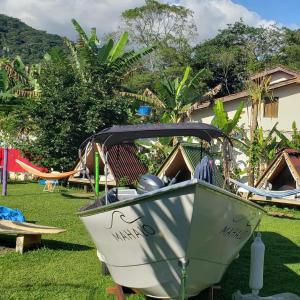 Un barco sentado en el césped de un patio. en Farah Hostel Suítes Camping Smartcamp e Passeio de barco, en Boicucanga