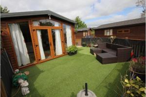 a small backyard with a lawn with a couch at Brambles Holiday Lodges in Paignton