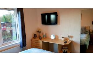 a bedroom with a desk and a tv on the wall at Brambles Holiday Lodges in Paignton