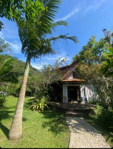 una casa con una palmera delante de ella en Casa da Floresta en Guarda do Embaú