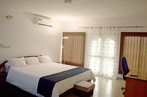 a bedroom with a white bed and a window at BAOBAB LODGE in Douala