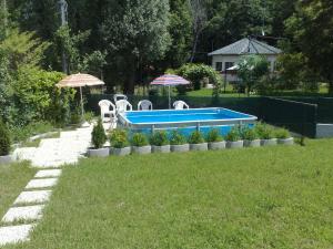 einen Pool im Garten mit Stühlen und Sonnenschirmen in der Unterkunft Appartamento Adriana in  Monvalle 