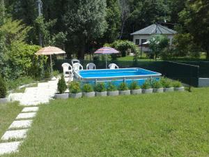 una piscina en un patio con sillas y sombrillas en Appartamento Giulia, en  Monvalle 