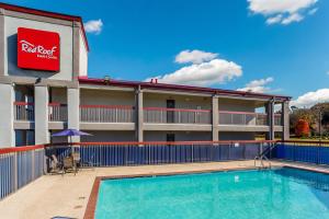 a pool in front of a hotel with a red roof at Red Roof Inn & Suites Athens, AL in Athens