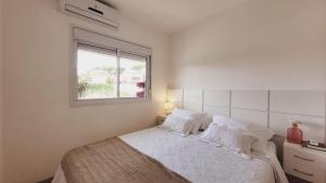 um quarto com uma cama com lençóis brancos e uma janela em Apartamento 50m2 Hospital Einstein Morumbi em São Paulo