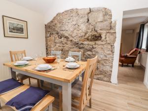 a dining room with a wooden table and a stone wall at Colomendy Alpaca Farm - Farm House in Mold
