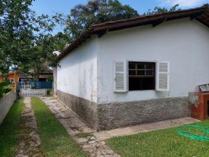 a white house with a window and a yard at 0321.03 - Lagoinha - Casa- Condomínio Salga - 2 Dormitórios - 8 Pessoas - 2 Quadras Do Mar in Ubatuba