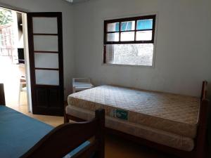 a bedroom with two beds and a window at 0321.03 - Lagoinha - Casa- Condomínio Salga - 2 Dormitórios - 8 Pessoas - 2 Quadras Do Mar in Ubatuba