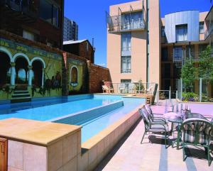 a swimming pool with tables and chairs next to a building at Melbourne Metropole Central Official in Melbourne