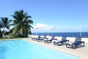 a pool with chairs and the ocean in the background at Pension de famille HITI MOANA VILLA in Papara