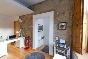 Habitación con pared de piedra, escritorio y silla. en 1930 City Lodge, en Oporto