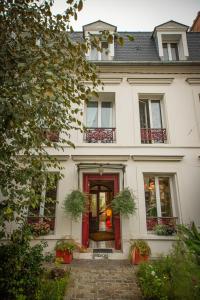 a white house with a red door and windows at Le Jardin des Toiles in Triel-sur-Seine