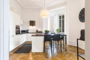 Appartement Luxueux Centre Ville في كولمار: مطبخ مع دواليب بيضاء وطاولة مع كراسي