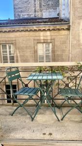 a green table and two chairs in front of a building at l'Appartement Grand Théatre in Bordeaux