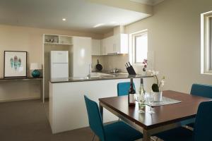 a kitchen and dining room with a table and blue chairs at Baileys Serviced Apartments in Perth