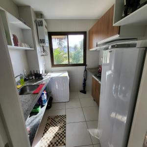 a kitchen with a white refrigerator and a window at VG Sun Cumbuco Bangalô E 201 adm Pessoa física in Cumbuco