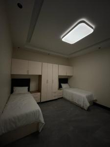 - une chambre avec 2 lits et une lumière au plafond dans l'établissement الأيبنوس EBONyشالية فندقي بصالة سينما ومسبح بجهاز تدفئة, à Khamis Mushait