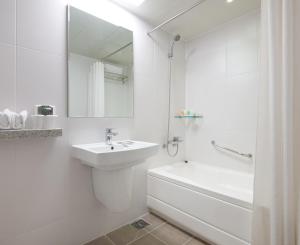 a white bathroom with a sink and a bath tub at Metro Hotel Myeongdong in Seoul