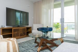 a living room with a glass table and a tv at Grenada Condo in Lower Woburn