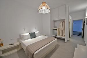 a white bedroom with a large bed and a chandelier at Kleri's apartments 5 in Tinos Town