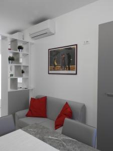 uma sala de estar com um sofá e almofadas vermelhas em Morena Studio Apartment em Asolo
