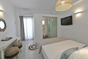 a white bedroom with a bed and two chairs at Kleri's apartments 2 in Tinos Town
