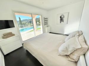 a white bedroom with a large bed and a television at Villa Le Clos des Lauriers in Roquebrune-Cap-Martin +25 photos