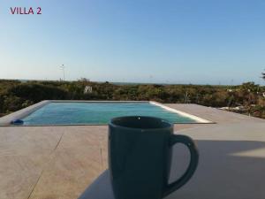 una taza de café en una mesa junto a la piscina en Villas Las Tunas 2 - Yucatan Home Rentals, en Uaymitun
