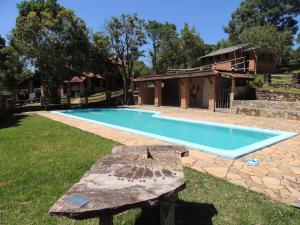 una piscina con panchina accanto a una casa di Reserva Canto da Vida Chalés e Camping a Lima Duarte