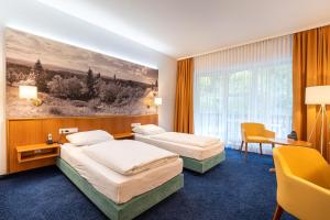 two beds in a hotel room with a painting on the wall at Hotel-Gasthof Hüttensteinach in Sonneberg