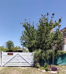 Une clôture blanche avec un arbre derrière elle dans l'établissement Cabaña Los Espinillos de San Isidro, à José de la Quintana