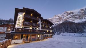 un hôtel dans les montagnes avec de la neige au sol dans l'établissement Hotel Wolf, à Selva di Val Gardena