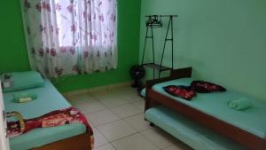 Habitación con 2 camas y pared verde. en Apartamento para até 05 pessoas no centro, en Teresópolis