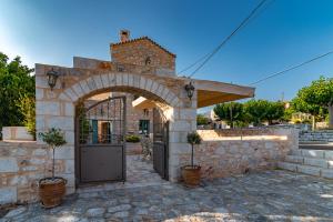 un accès à un bâtiment en pierre avec une arche dans l'établissement Olea, à Pirgos Dhirou