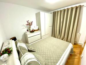 a bedroom with a bed and a dresser and curtains at Home away - Chic and Cozy Apartment in Constanţa