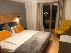 ein Schlafzimmer mit einem Bett und einem gelben Stuhl in der Unterkunft Apart EMMA in Finkenberg