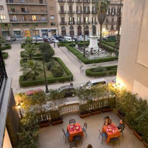 two people sitting at tables in a balcony of a building at Hotel Joli in Palermo
