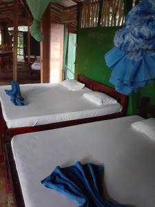 a room with two beds and a table covered in blankets at River Side Cabana in Tissamaharama