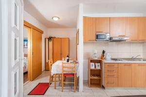 uma cozinha com uma mesa e uma cozinha com um micro-ondas em Apartments Tolic em Baska Voda
