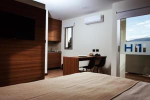 a bedroom with a bed and a desk with a television at H1 Apartments Hotel in San Fernando del Valle de Catamarca