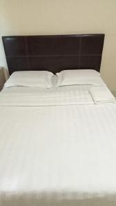 a bed with white sheets and a black headboard at Hotel Ocean in Lahad Datu