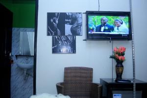 une télévision sur un mur avec des photos dans l'établissement Awooooo Accommodation Kampala, à Kampala