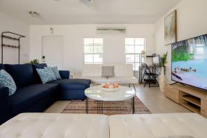 a living room with a blue couch and a tv at Art Deco Themed Vacation Home w Sauna, Huge Terrace, & Outdoor BBQ Kitchen in Hallandale Beach