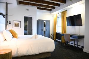 a bedroom with a bed and a desk and a television at Hotel Le Bloc in Quebec City