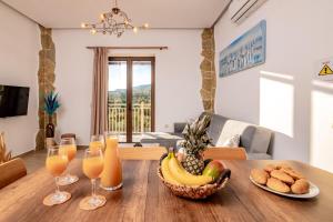 una mesa con un bol de fruta y vasos de zumo de naranja en Villa Foteini en Skinária