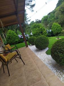 eine Terrasse mit einem Stuhl und einen Garten mit Büschen in der Unterkunft KasaBella Monte Verde in Monte Verde