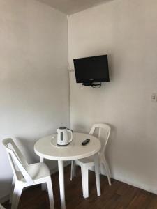 a white table with two chairs and a tv on a wall at Departamentos LT3 in Las Toscas