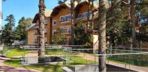 a building with trees in front of a tennis court at Apartamento em Gramado com piscina in Gramado