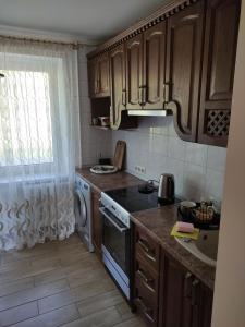 a kitchen with wooden cabinets and a stove top oven at Тисовець квартира in Tysovets