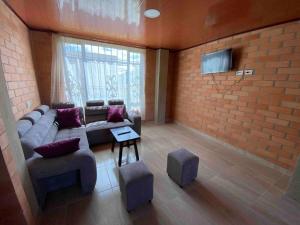 ein Wohnzimmer mit Sofa und Ziegelwand in der Unterkunft Hotel Villa Stella "Apartamentos y habitaciones" in Paipa
